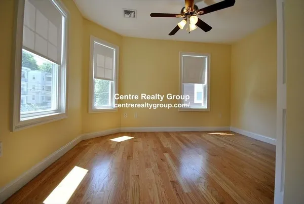 a view of an empty room with a window and wooden floor