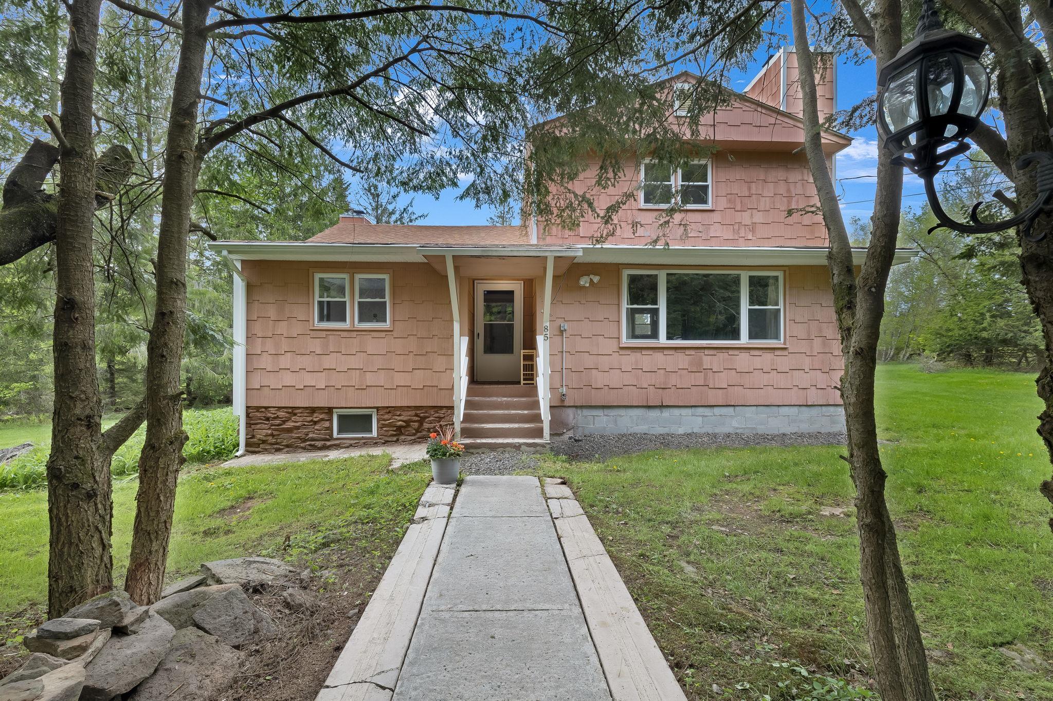 View of front of home with a front yard, a shingled roof, and a chimney