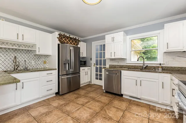 a kitchen with granite countertop stainless steel appliances a refrigerator sink and microwave