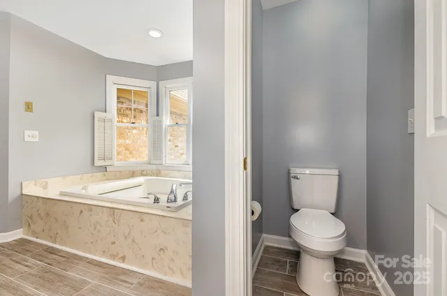 a bathroom with a granite countertop toilet a sink and a window