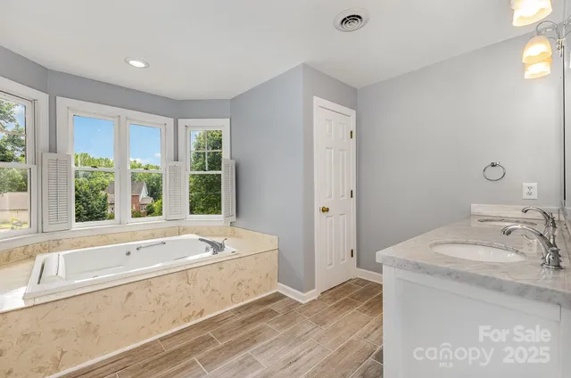 a bathroom with a tub sink and large window