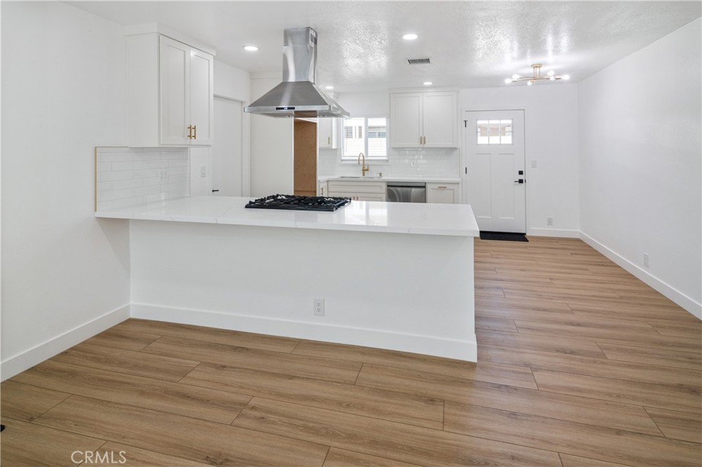 11452 Earlham Street Orange, CA 92869 - Photo 17 of 30 a view of a kitchen with kitchen island a sink wooden floor and a large window
