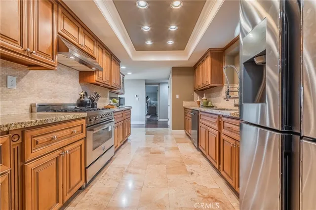 a kitchen with stainless steel appliances granite countertop a refrigerator a stove and a sink