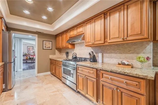 a kitchen with granite countertop stainless steel appliances a sink stove and cabinets