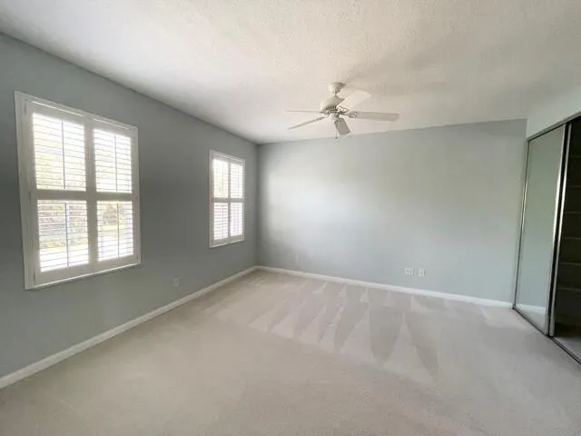 an empty room with windows and fan