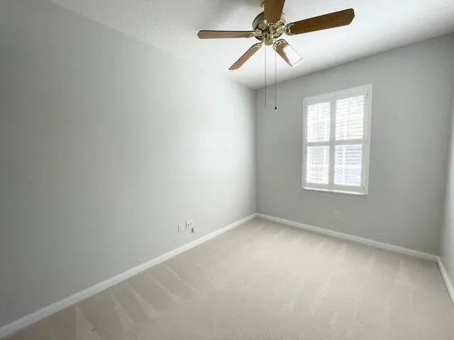 an empty room with a window and a fan