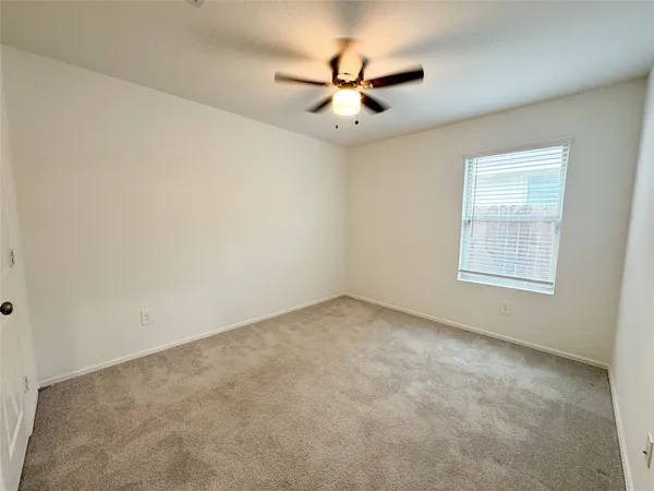 an empty room with a window and a fan