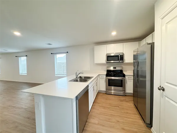 a large kitchen with a center island wooden floor and stainless steel appliances