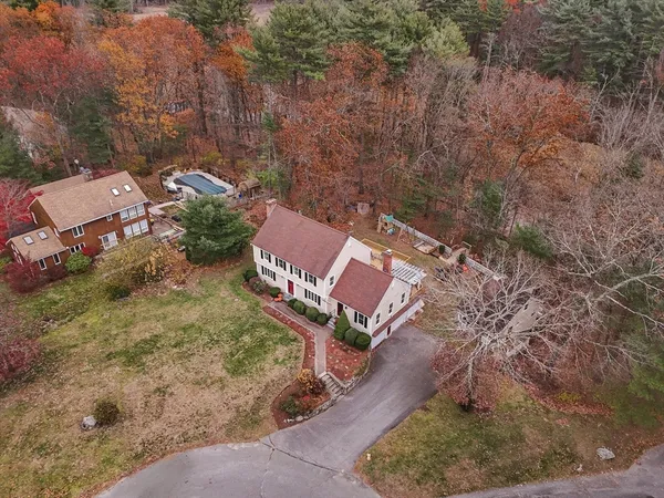 an aerial view of a house with a yard and large tree