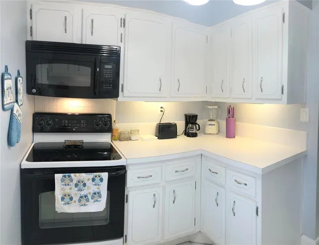 a kitchen with white cabinets and black appliances