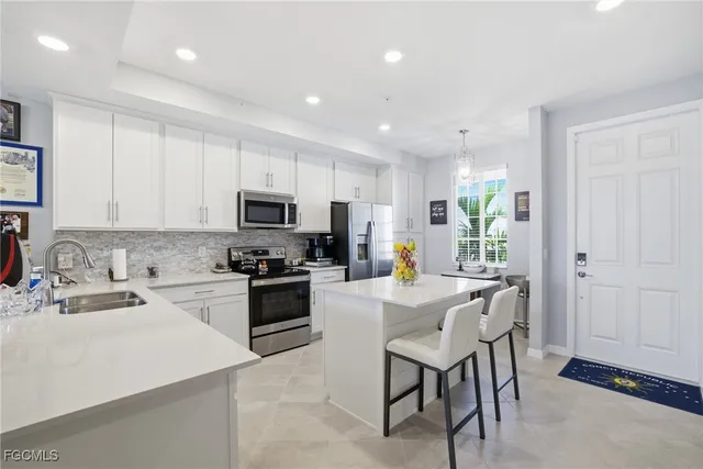 a kitchen with stainless steel appliances granite countertop a stove top oven a sink a refrigerator with white cabinets and wooden floor