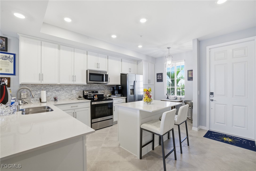 43993 Boardwalk Loop, Unit 1925 Punta Gorda, FL 33982 - Photo 13 of 35 a kitchen with stainless steel appliances granite countertop a stove top oven a sink a refrigerator with white cabinets and wooden floor