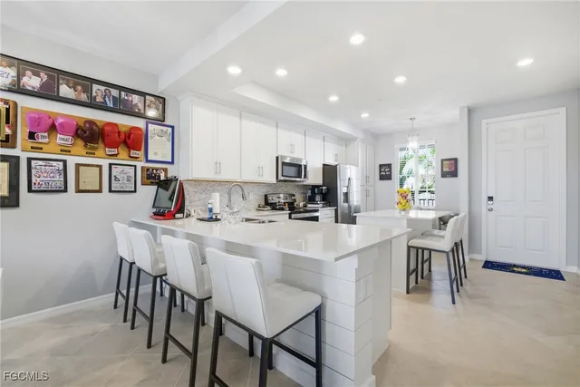 a kitchen with stainless steel appliances a dining table chairs and a refrigerator