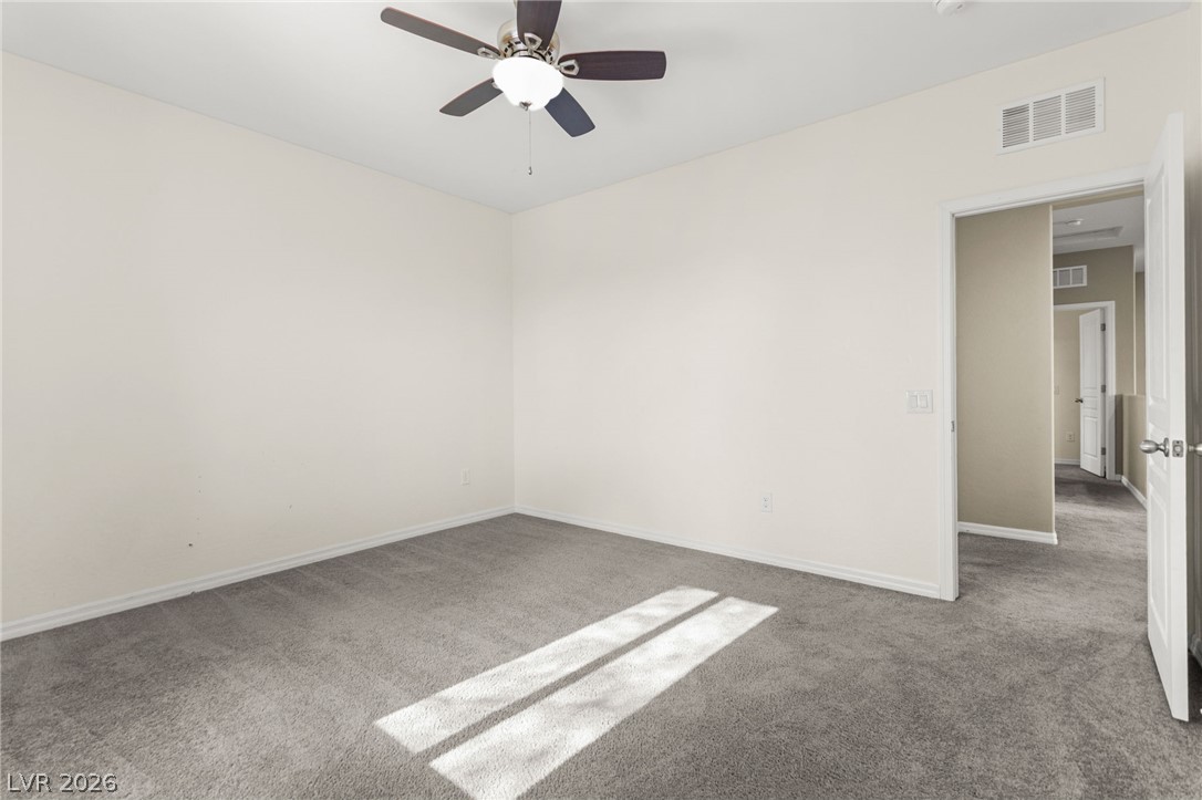 11048 Prairie Grove Road Las Vegas, NV 89179 - Photo 52 of 75 A spacious room featuring comfortable carpeted flooring and an overhead ceiling fan.