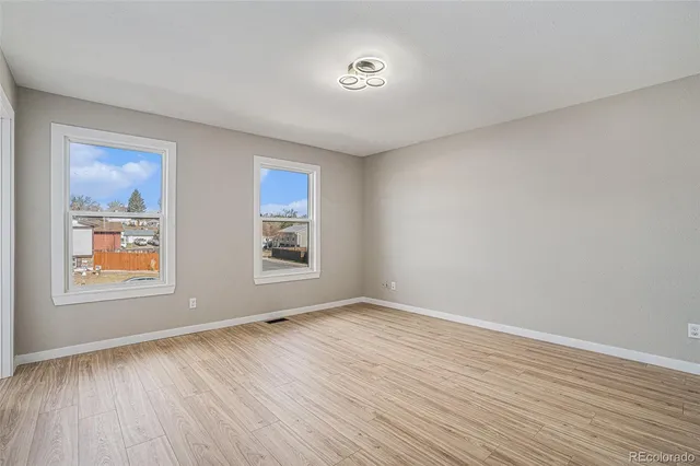 an empty room with wooden floor and windows