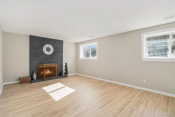 a view of an empty room with wooden floor fireplace and a window