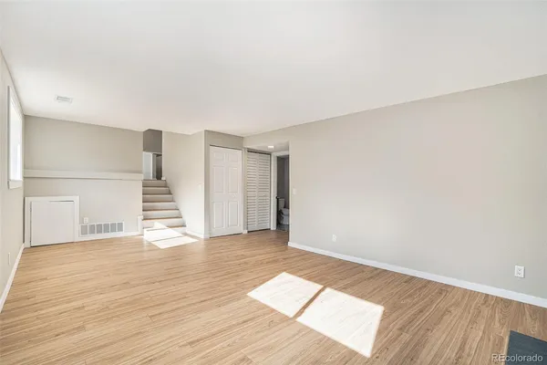 a view of an empty room with wooden floor and stairs