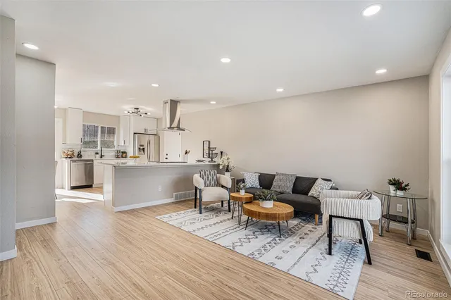 a living room with lots of furniture and view of kitchen appliances