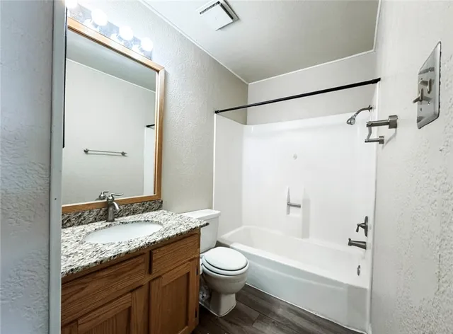 a bathroom with a granite countertop sink toilet and shower