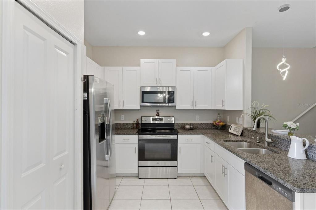 8606 Reedville Street New Port Richey, FL 34654 - Photo 13 of 100 a kitchen with stainless steel appliances granite countertop a stove a sink and a refrigerator