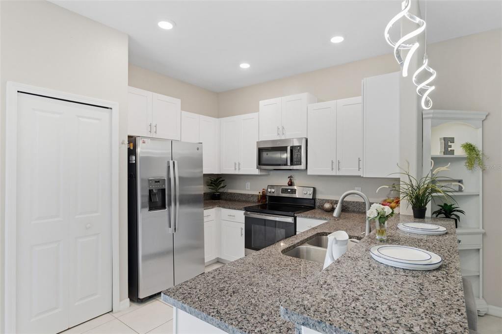 8606 Reedville Street New Port Richey, FL 34654 - Photo 14 of 100 a kitchen with stainless steel appliances granite countertop a refrigerator a stove a sink a stove a dining table and chairs