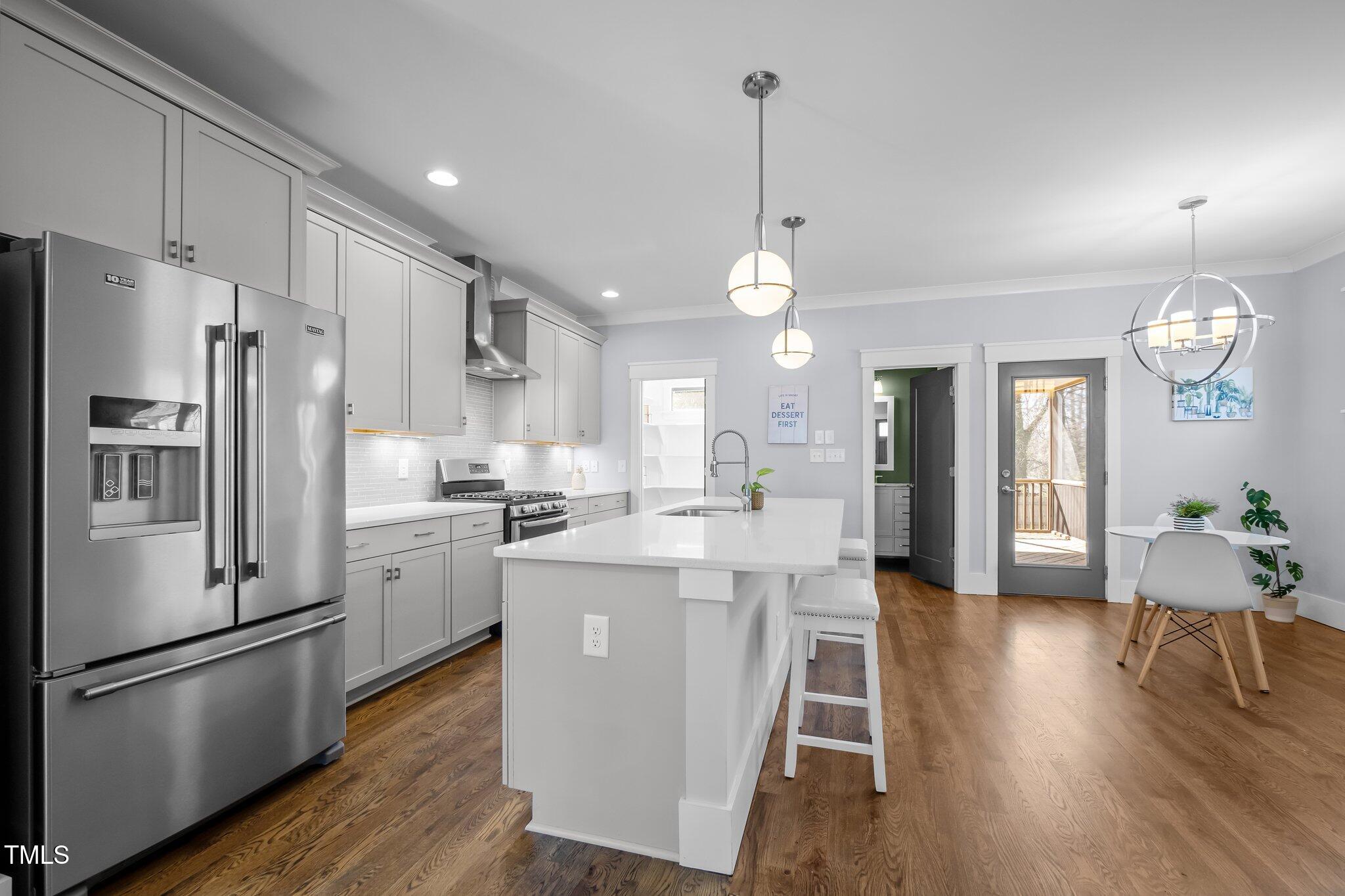 608 Dowd Street Durham, NC 27701 - Photo 5 of 24 a kitchen with stainless steel appliances a refrigerator a stove a sink dishwasher and a dining table with wooden floor