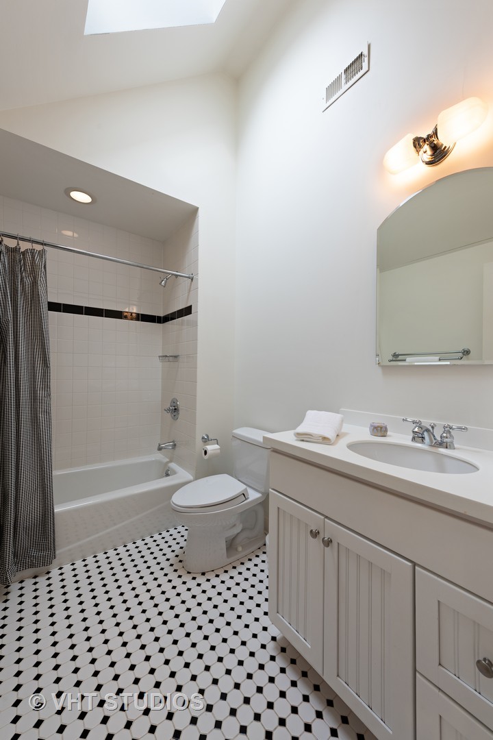 1075 Elm Street Winnetka, IL 60093 - Photo 28 of 40 a bathroom with a sink a toilet a shower and a mirror