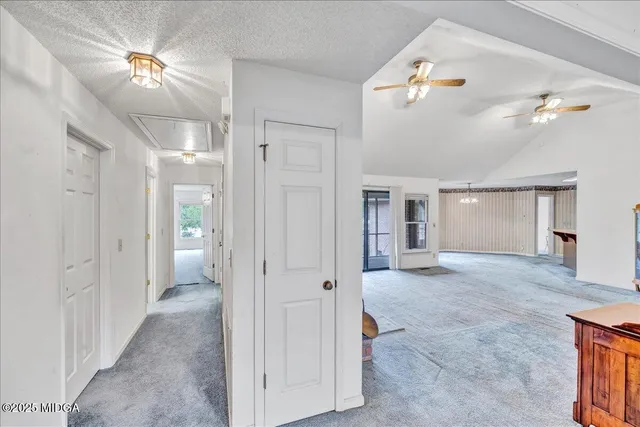 en empty room with chandelier fan and windows