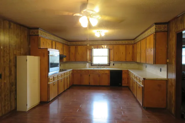 a kitchen with stainless steel appliances granite countertop a refrigerator a sink dishwasher a stove with wooden cabinets and wooden floor