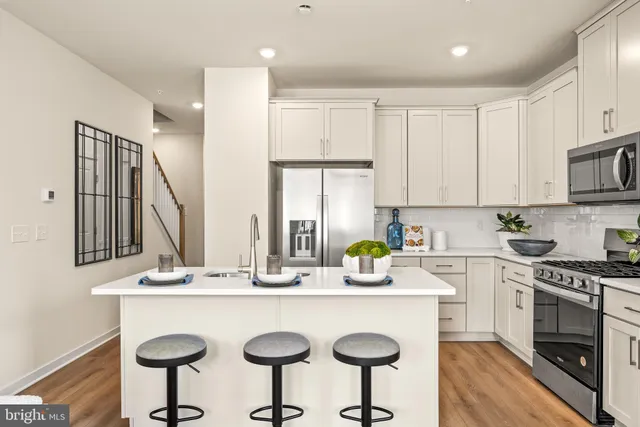 a kitchen with stainless steel appliances a sink a stove a microwave a refrigerator and cabinets