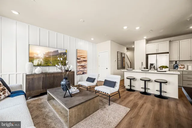 a living room with furniture a flat screen tv and kitchen view
