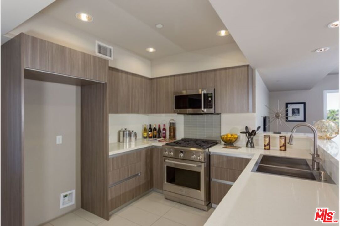 a kitchen with stainless steel appliances a refrigerator a stove top oven a sink and cabinets