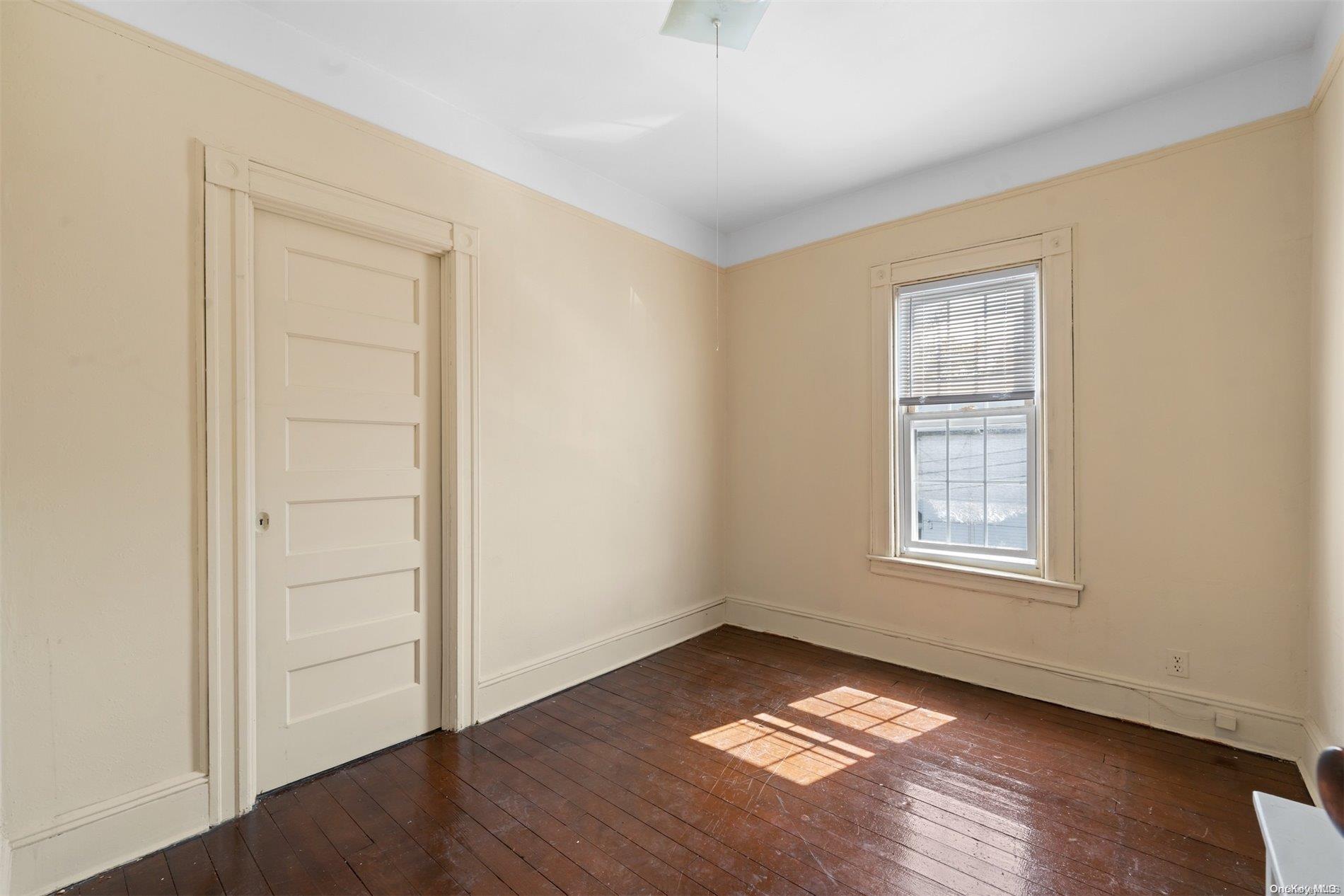 85-70 79th Street Queens, NY 11421 - Photo 13 of 18 an empty room with wooden floor and windows