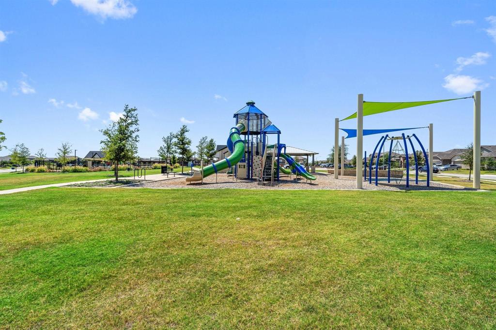 15932 Stableford Road Justin, TX 76247 - Photo 29 of 35 Expansive green space featuring a playground with a slide, climbing structures, and shade canopies