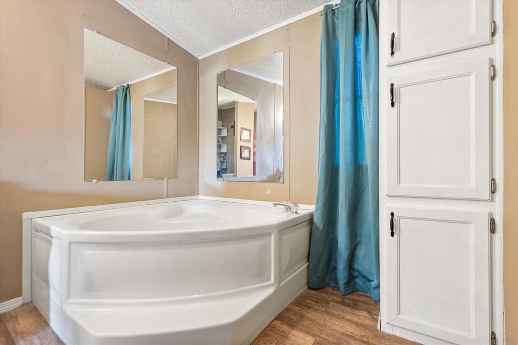 309 Southeast County Road Corsicana, TX 75109 - Photo 21 of 27 Corner soaking tub with wood-finish flooring and integrated cabinetry