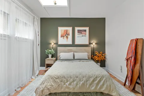 a bedroom with a bed and a flat tv screen on the dresser