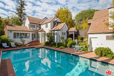 a front view of a house with garden and swimming pool