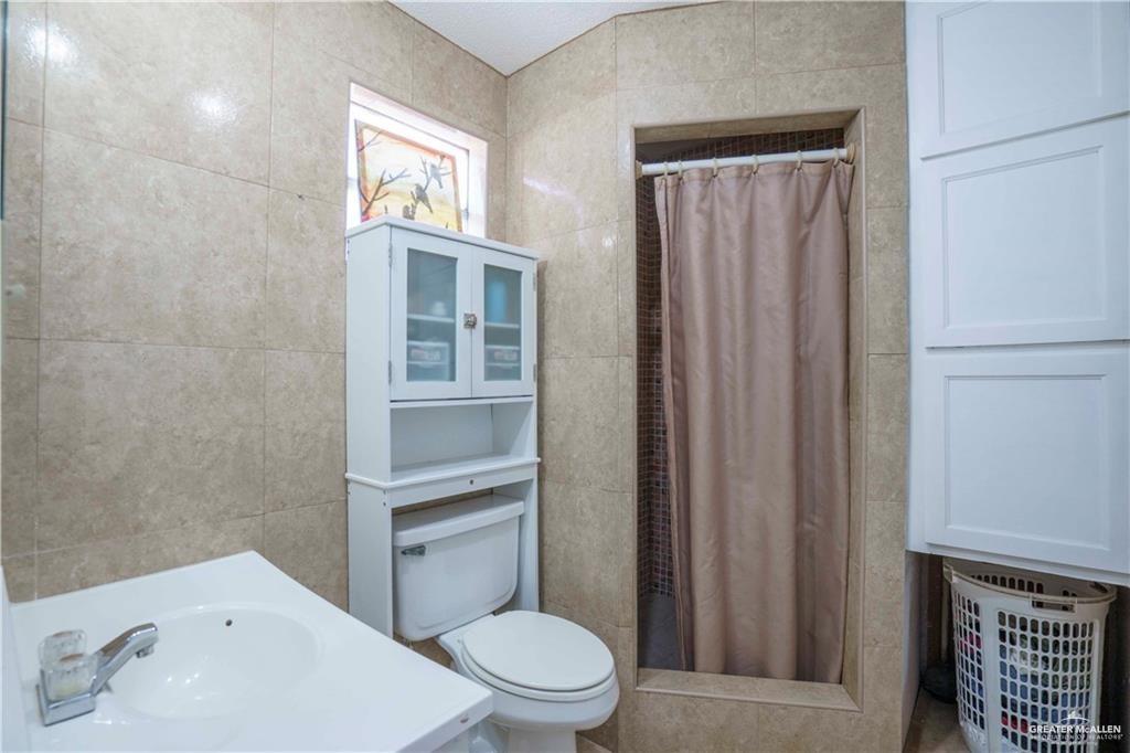 15 El Mesquite Lane Rio Grande City, TX 78582 - Photo 11 of 30 a white toilet sitting next to a bathroom sink and vanity