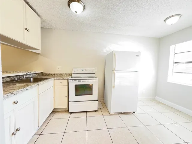 a kitchen with granite countertop white cabinets and white appliances