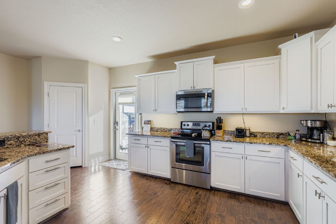 19004 Mariners Point Lago Vista, TX 78645 - Photo 11 of 23 a kitchen with white cabinets and white appliances