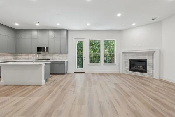 a view of an empty room with wooden floor fireplace and a window