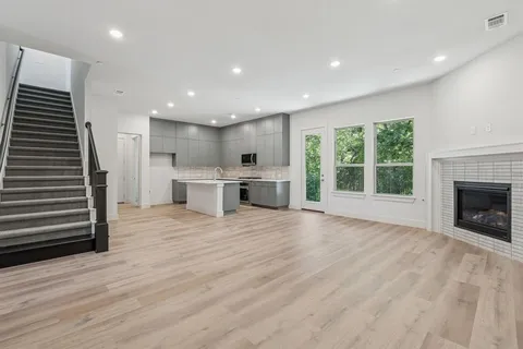 an empty room with wooden floor a fireplace and windows