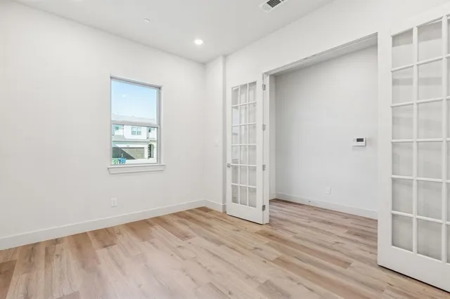 an empty room with wooden floor and windows