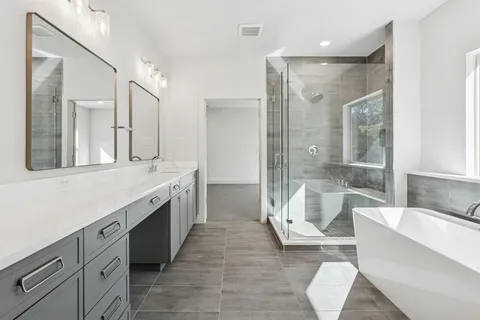 a spacious bathroom with a double vanity sink a large mirror and a bathtub