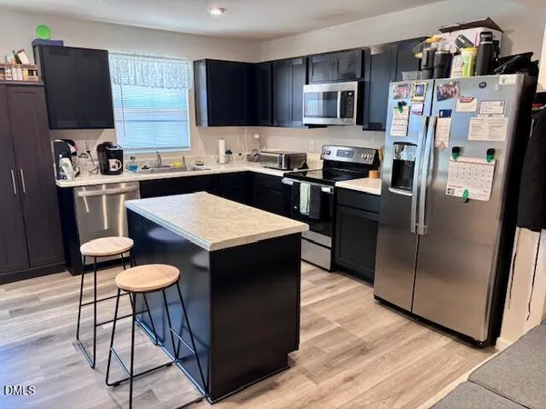 a kitchen with stainless steel appliances kitchen island granite countertop a refrigerator a stove a sink a microwave and island