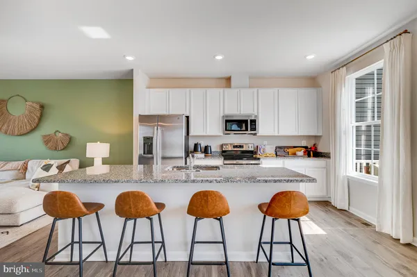 a kitchen with stainless steel appliances kitchen island granite countertop a dining table chairs and a refrigerator