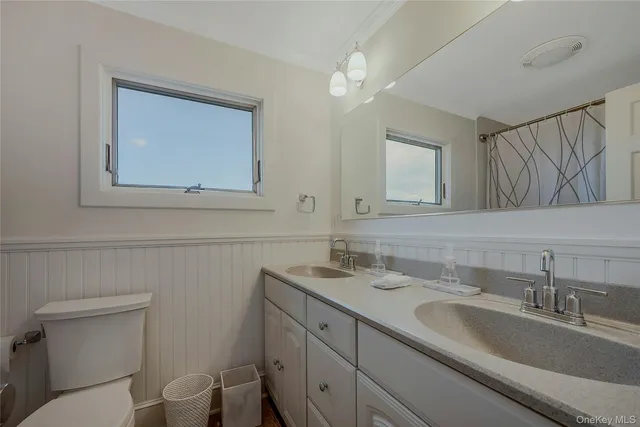 a bathroom with a toilet a sink a mirror and vanity