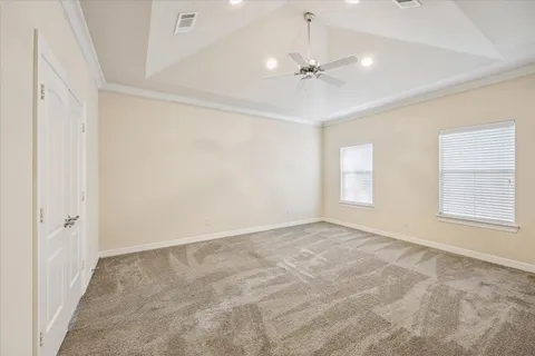 an empty room with chandelier fan and windows