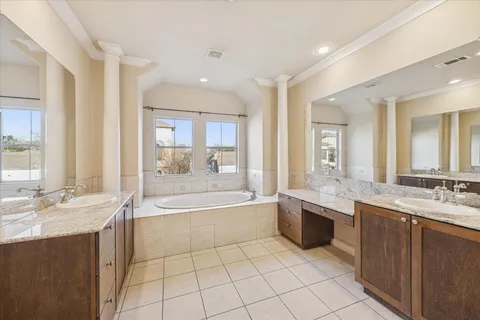 a large bathroom with a granite countertop double vanity sink a bathtub and window