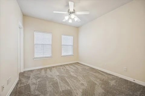 an empty room with windows and chandelier fan